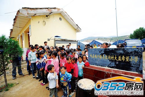 學生在等候領取救援物資,他們身旁的教室已成危房。